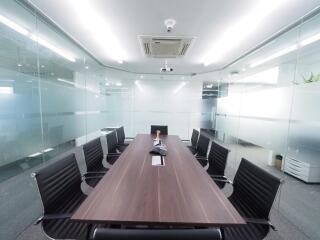 Modern conference room with a large wooden table and black chairs