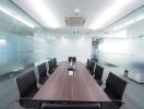 Modern conference room with a large wooden table and black chairs