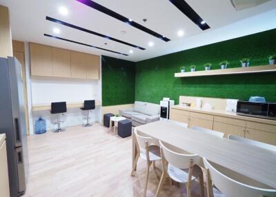 Modern kitchen with dining area, vibrant green wall, and wooden flooring