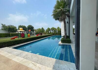 Luxurious outdoor pool beside a modern residence with a playground in the background