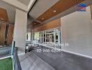 Modern building entrance with a spacious covered walkway, wooden ceiling panels, and tiled flooring