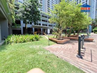 Lush garden and seating area in a residential community with modern buildings in the background