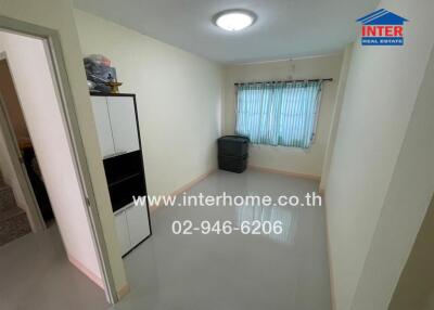 A small, empty room with a window, light fixture, and a white storage cabinet