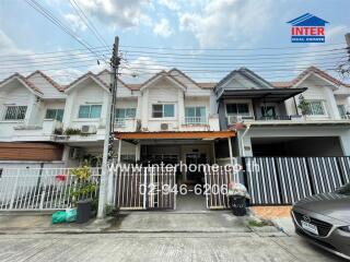 Townhouse exterior view showing front facade with parking space and gated entrance