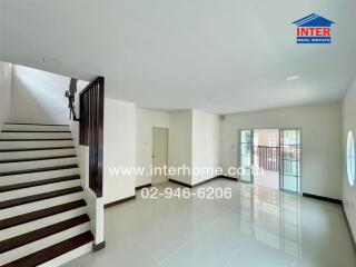 Spacious living room with staircase and ample natural light