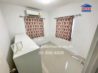 Compact laundry room with modern appliances and decorative curtains