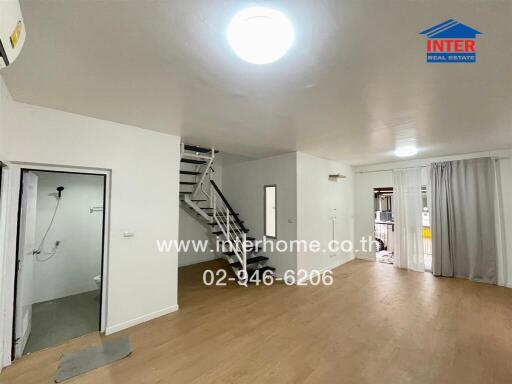 Spacious and well-lit living room with an open staircase and minimalist decor