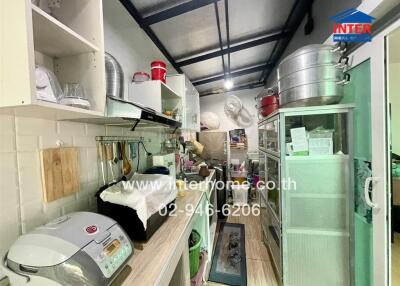 Narrow and fully equipped kitchen with storage shelves and appliances