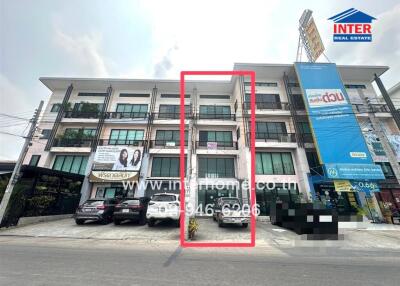 Modern commercial building exterior with parked cars and visible signage