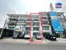 Modern commercial building exterior with parked cars and visible signage