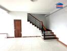 Spacious living area with white tiles and a wooden staircase