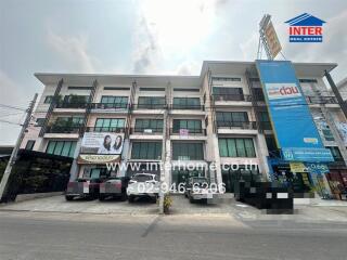 Exterior view of a modern commercial building with multiple units and parked cars