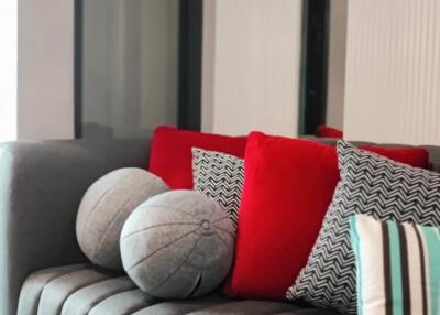 Elegant living room with grey sofa and vibrant red cushions