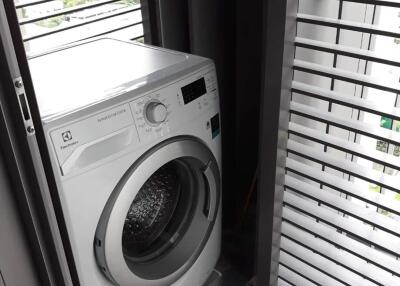 Compact laundry area with modern washing machine and louvered window blinds