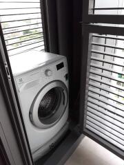 Compact laundry area with modern washing machine and louvered window blinds