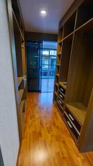 Well-lit hallway with wooden flooring and built-in shelves leading to a balcony