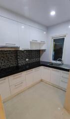 Modern kitchen with white cabinetry and black backsplash