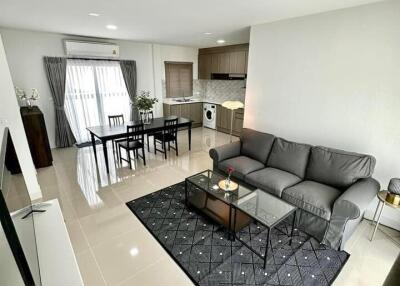 Spacious open concept living room with kitchen, featuring modern furniture and abundant natural light