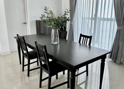 Modern dining room with black table and chairs, crisp white walls, and elegant grey curtains