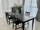 Modern dining room with black table and chairs, crisp white walls, and elegant grey curtains