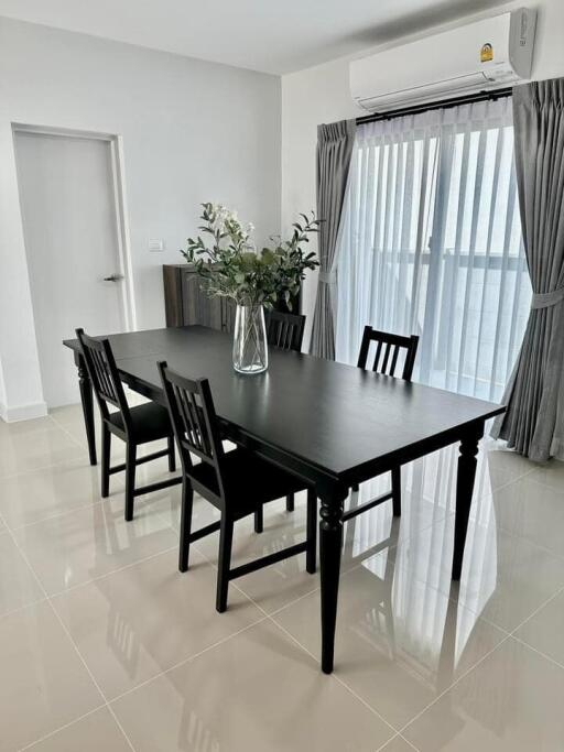 Modern dining room with black table and chairs, crisp white walls, and elegant grey curtains