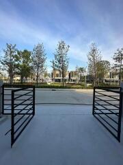 Outdoor view of modern residential complex with open gate and landscaped gardens