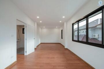 Spacious bedroom with wooden flooring and ample natural light