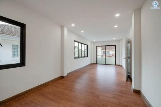 Spacious and brightly lit living room with hardwood floors and multiple windows