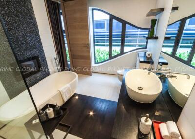 Modern bathroom with wooden floors, round freestanding tub, and sleek fixtures