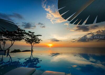 Luxurious infinity pool overlooking sunset with ocean view