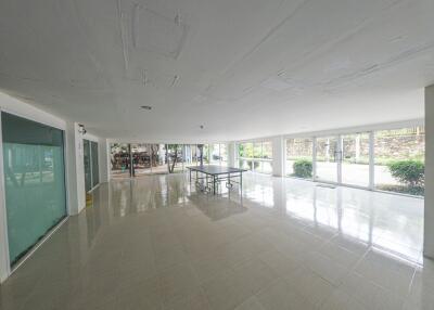 Spacious and well-lit empty commercial space with large windows and reflective tile flooring