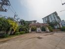 Exterior view of a residential complex with security gate and lush landscaping