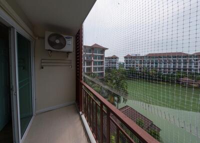 Spacious balcony with protective netting overlooking green landscape and residential buildings