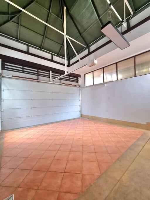 Spacious garage with red tiled floor and industrial style roof