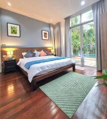 Spacious bedroom with polished wooden floor and garden view