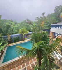 Tropical outdoor pool area with lush greenery and rainy weather