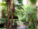 Lush garden pathway with tropical plants and shaded seating area in a residential complex