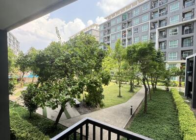 View from the apartment balcony showcasing lush green landscaping and residential building