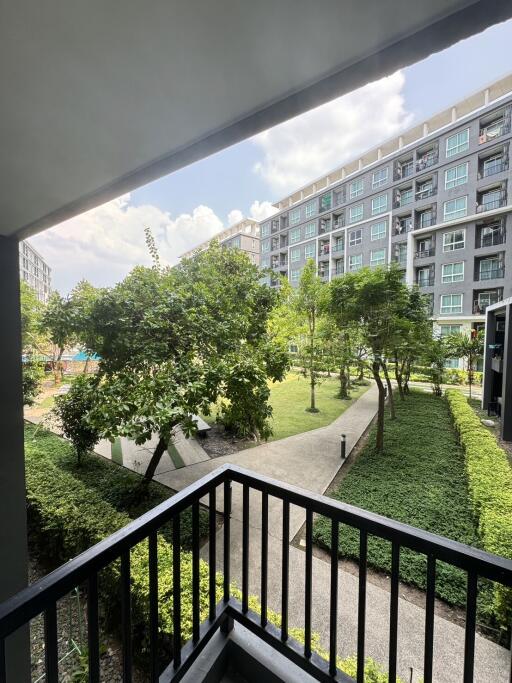 View from the apartment balcony showcasing lush green landscaping and residential building