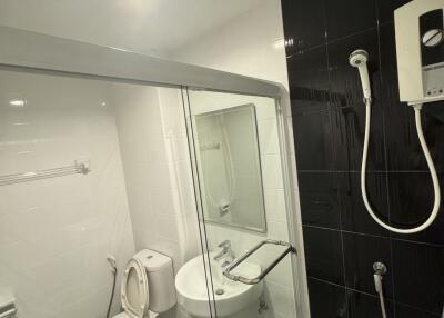 Modern bathroom with black and white tiles, shower, and essential fixtures