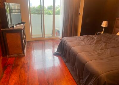 Spacious bedroom with glossy hardwood floor and balcony access