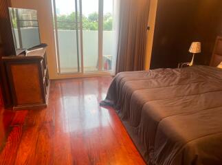 Spacious bedroom with glossy hardwood floor and balcony access