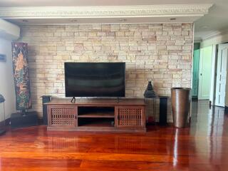 Spacious living room with stone wall and hardwood floors
