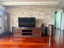 Spacious living room with stone wall and hardwood floors