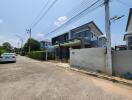 Modern two-story house with balcony and driveway in a residential area