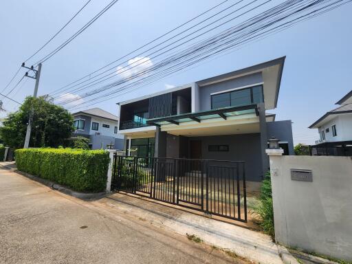 Modern two-story residential home with lush garden and secure gate