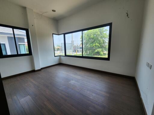 Empty bedroom with wooden floor and large windows