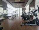 Well-equipped gym with various exercise machines and large windows