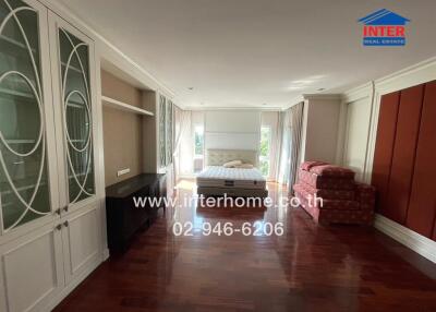 Spacious and well-lit bedroom with hardwood floors and built-in cabinetry