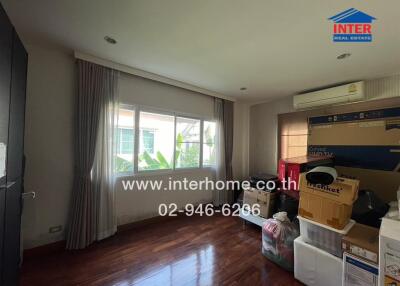 Bedroom with wooden floor, large window, and some unpacked boxes